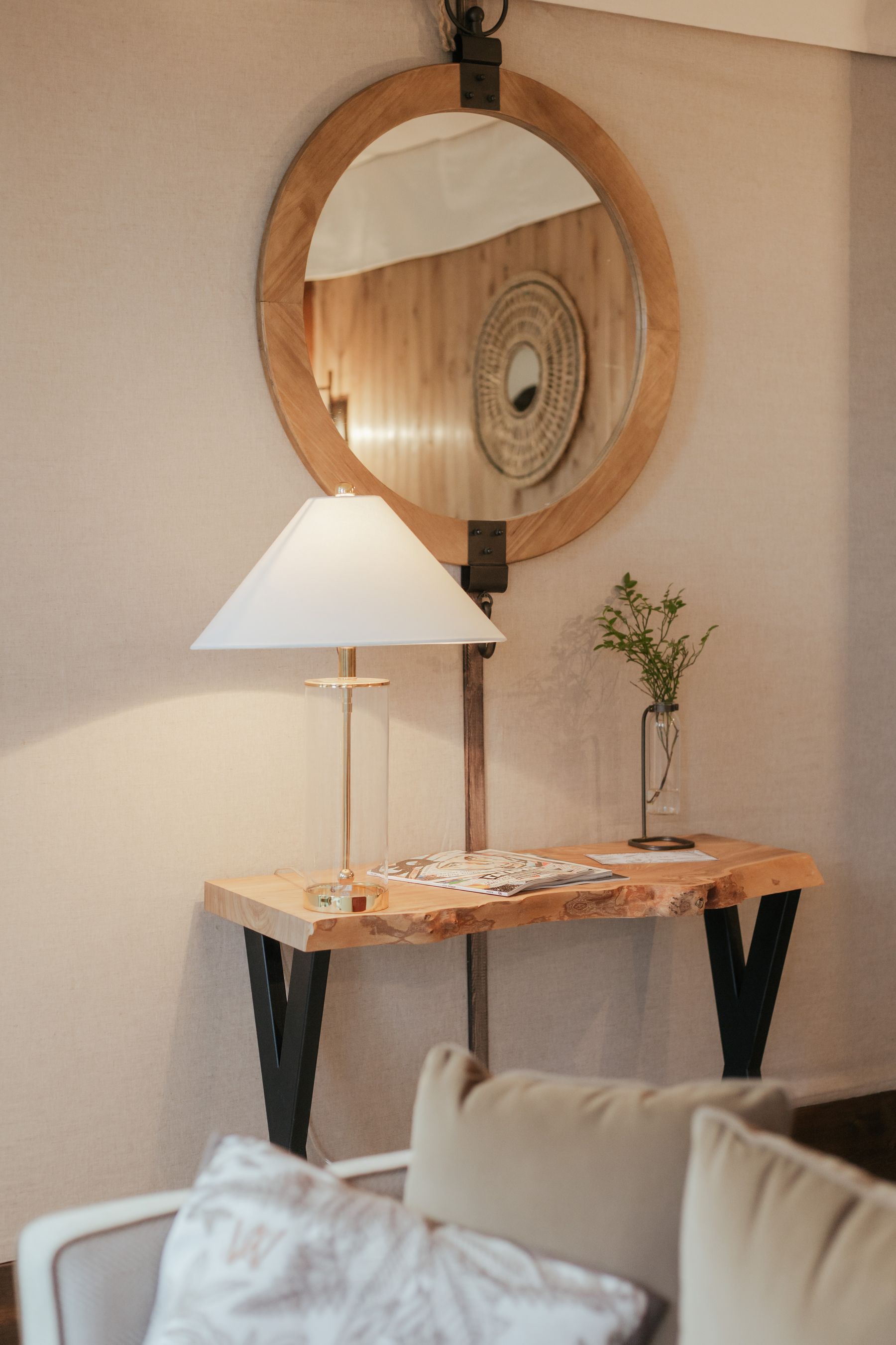 Warm lamp light against a sculptural mirror and natural materials